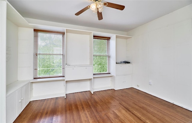 empty room featuring a ceiling fan, a healthy amount of sunlight, and wood finished floors