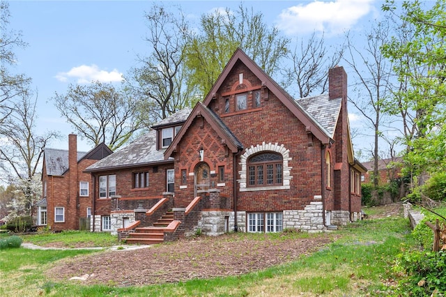 tudor house featuring a high end roof, brick siding, and a chimney