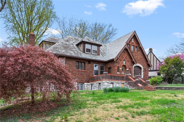 back of property featuring brick siding, a high end roof, and a chimney