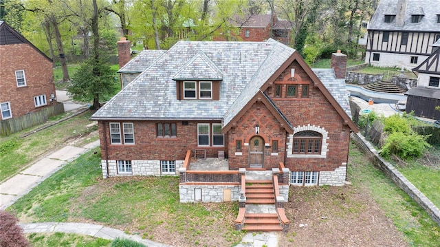 english style home featuring brick siding and a chimney
