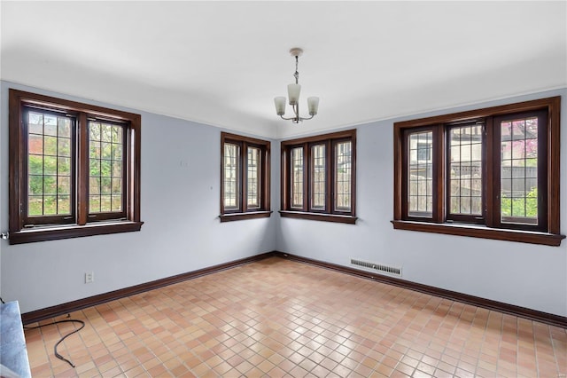 empty room featuring a chandelier, baseboards, and visible vents
