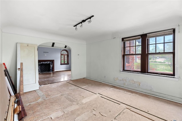unfurnished room featuring arched walkways and a high end fireplace