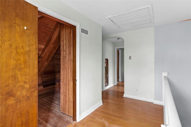 hall featuring an upstairs landing, attic access, visible vents, and wood finished floors