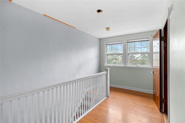 corridor featuring an upstairs landing, wood finished floors, and baseboards