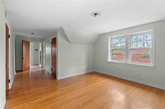 bonus room with light wood-type flooring, visible vents, baseboards, and lofted ceiling