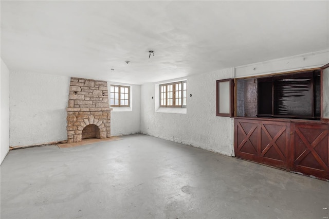 unfurnished living room featuring a fireplace, concrete flooring, and a textured wall