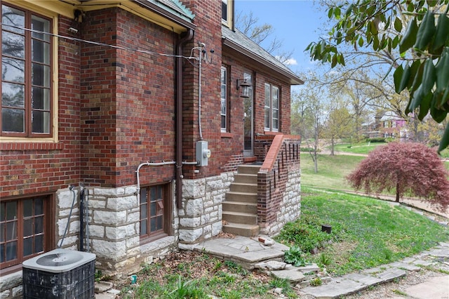 view of home's exterior with brick siding, central AC unit, and stairs