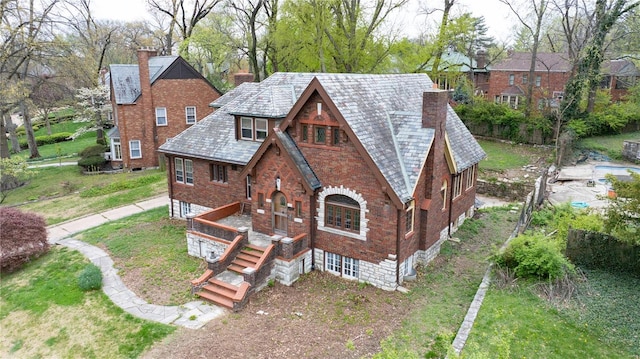 exterior space with a front lawn, a high end roof, brick siding, and a chimney