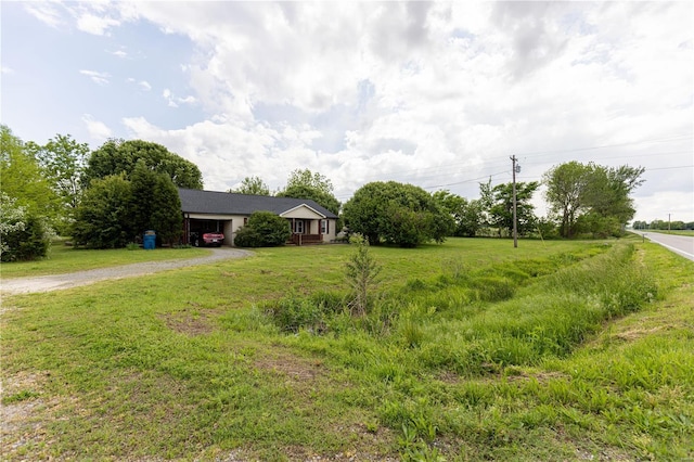 view of front of home with dirt driveway, a front lawn, and an attached garage