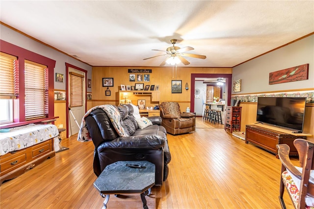 living room with crown molding, wood walls, ceiling fan, and hardwood / wood-style flooring