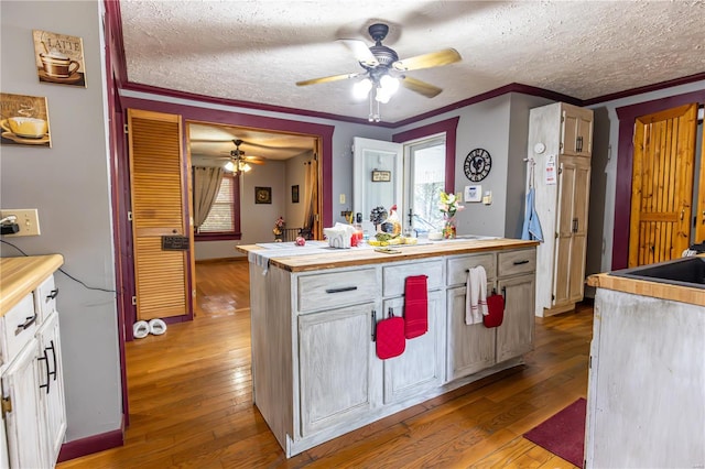 kitchen with ceiling fan, a textured ceiling, wood-type flooring, and wooden counters