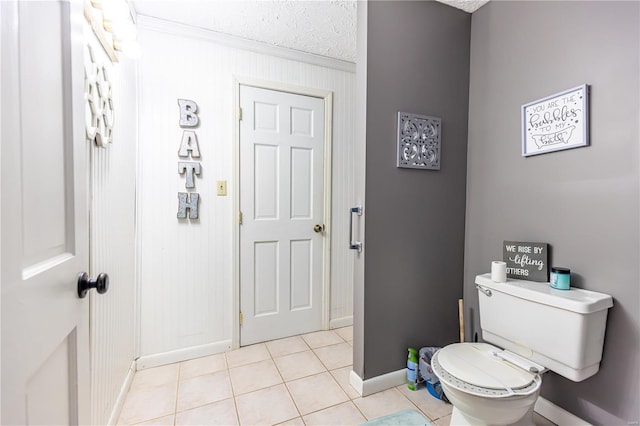bathroom with tile patterned flooring, a textured ceiling, baseboards, and toilet