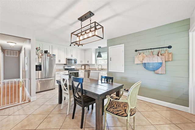 dining space featuring a textured ceiling, visible vents, baseboards, and light tile patterned flooring