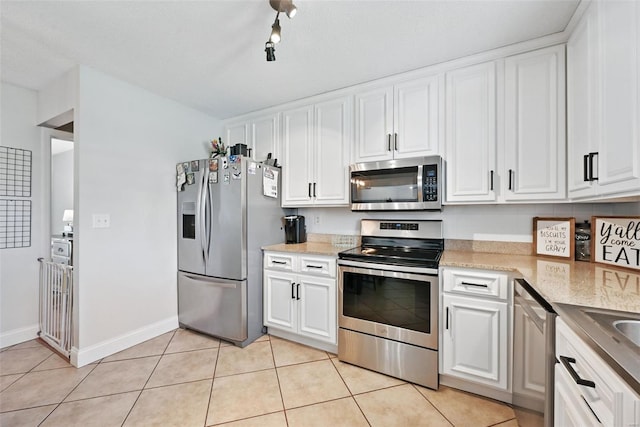 kitchen with baseboards, white cabinets, light tile patterned floors, and appliances with stainless steel finishes
