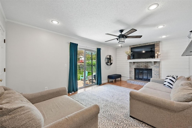 living area featuring a ceiling fan, a fireplace, and a textured ceiling