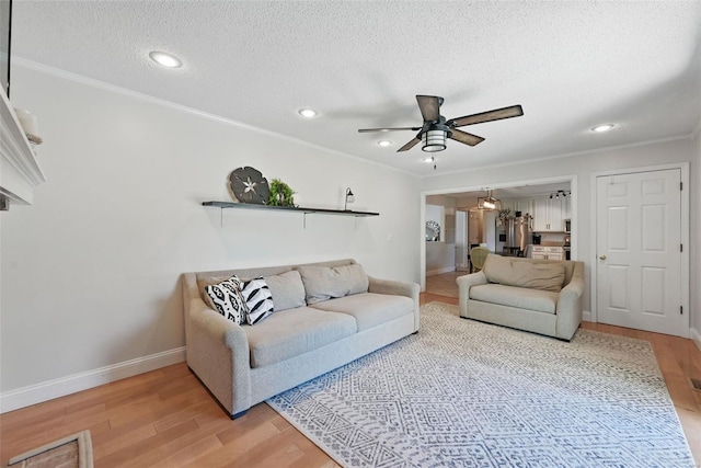 living area featuring light wood-type flooring, baseboards, crown molding, and ceiling fan