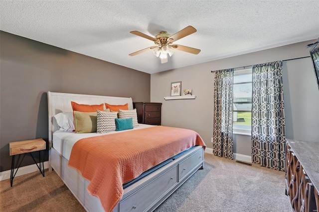 bedroom with ceiling fan, a textured ceiling, carpet flooring, and baseboards