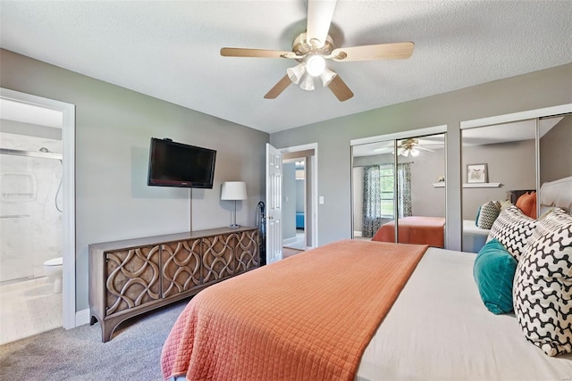 bedroom with carpet flooring, a ceiling fan, two closets, ensuite bathroom, and a textured ceiling