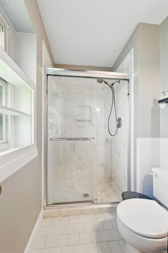 bathroom with a stall shower, toilet, and tile patterned floors