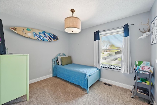 carpeted bedroom featuring baseboards, visible vents, and a textured ceiling
