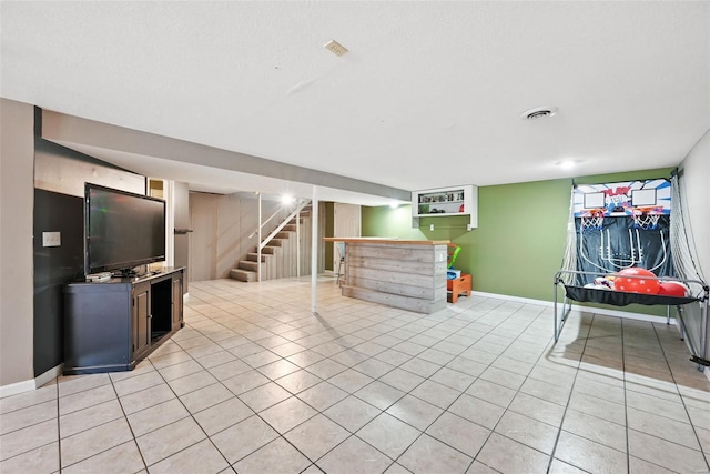 interior space with a dry bar, baseboards, visible vents, light tile patterned flooring, and stairway