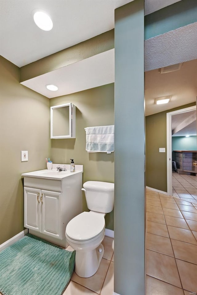 bathroom featuring vanity, toilet, baseboards, and tile patterned floors
