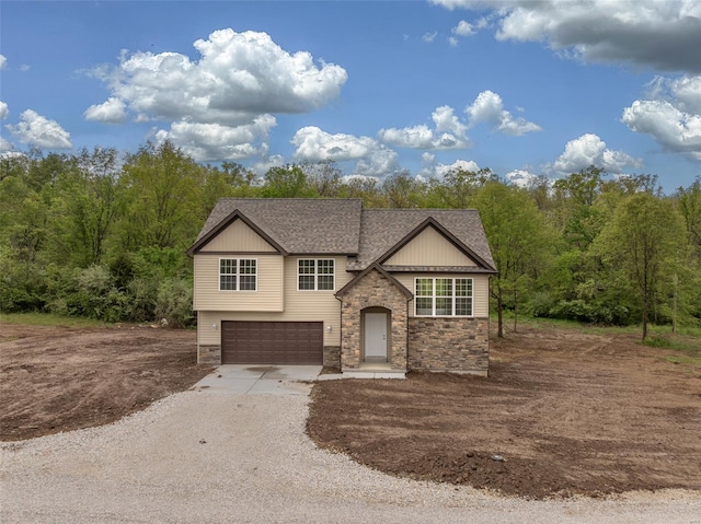 view of front of house featuring stone siding, roof with shingles, driveway, and a garage
