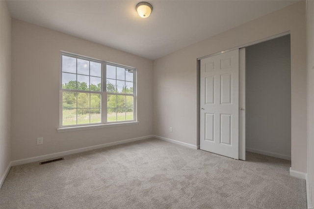 unfurnished bedroom featuring a closet, visible vents, baseboards, and carpet floors