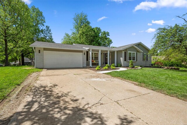 ranch-style house featuring a garage, concrete driveway, a front lawn, and covered porch