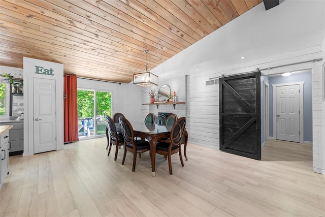 dining space with vaulted ceiling, wood ceiling, a barn door, and light wood-type flooring