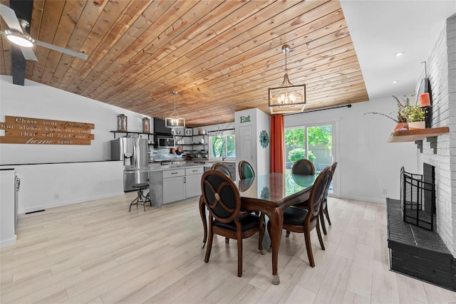 dining room featuring lofted ceiling, a chandelier, wooden ceiling, light wood-style floors, and a brick fireplace