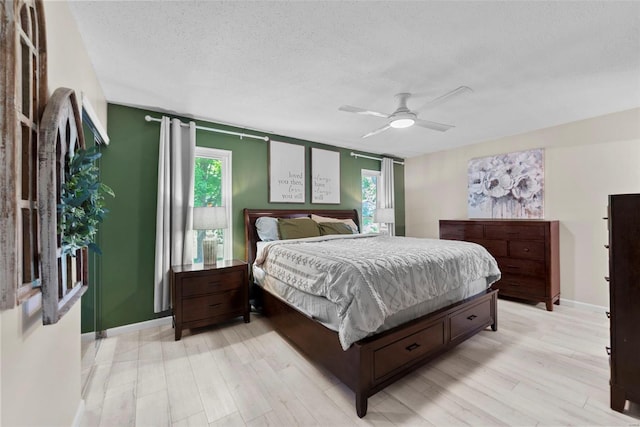 bedroom featuring a textured ceiling, light wood-style flooring, ceiling fan, and baseboards