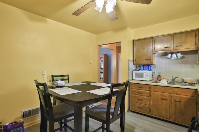 dining area with light wood finished floors and ceiling fan