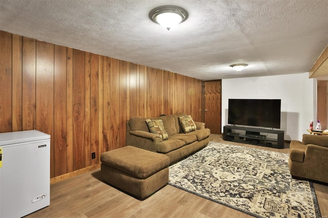 living room featuring wood finished floors, a textured ceiling, wood walls, and baseboards
