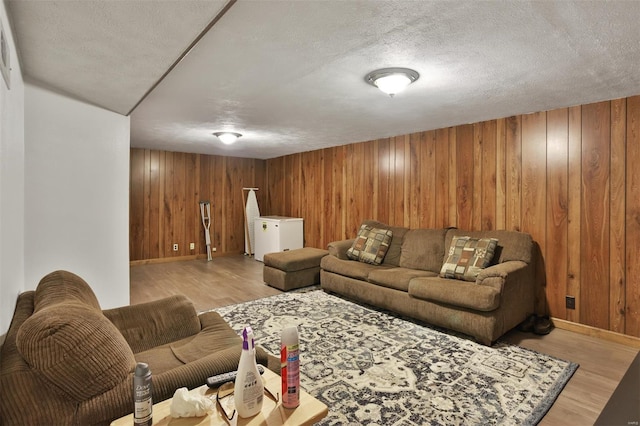 living area with wood finished floors, baseboards, wood walls, and a textured ceiling