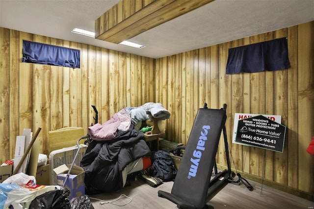miscellaneous room featuring wooden walls, wood finished floors, and baseboards