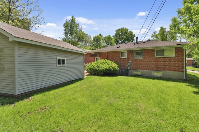 rear view of property featuring a lawn, central air condition unit, and brick siding