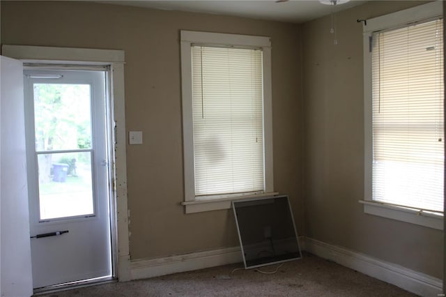 entryway with ceiling fan, carpet, and baseboards