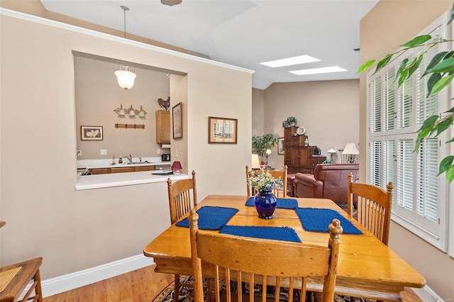 dining area with baseboards, a skylight, and wood finished floors