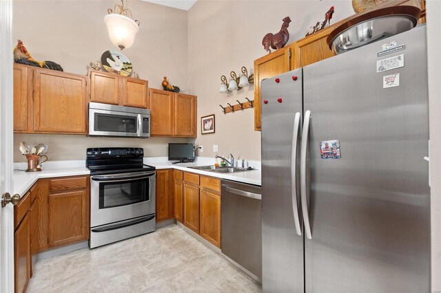 kitchen with light countertops, stainless steel appliances, brown cabinets, and a sink