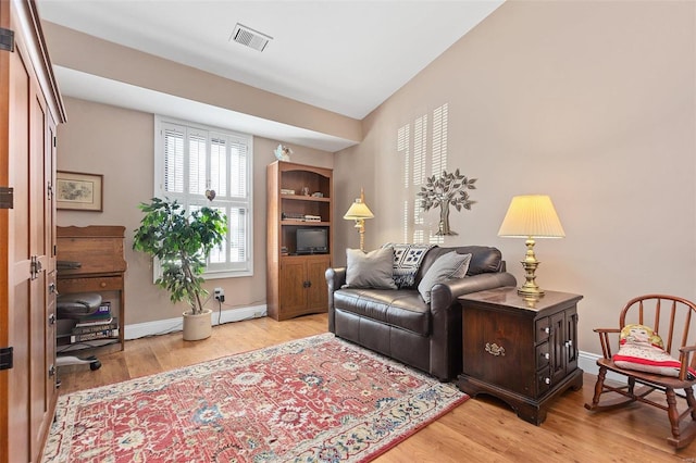 living area featuring light wood finished floors, visible vents, and baseboards