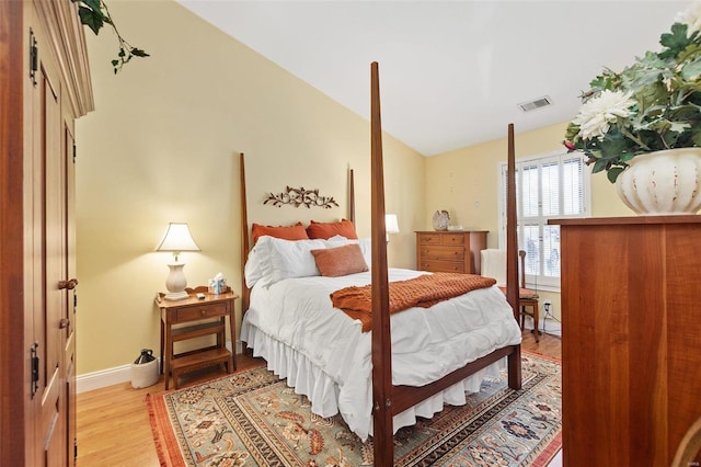 bedroom featuring vaulted ceiling, light wood-style flooring, baseboards, and visible vents