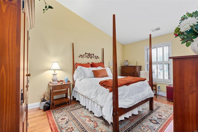 bedroom with baseboards, light wood-style floors, visible vents, and vaulted ceiling