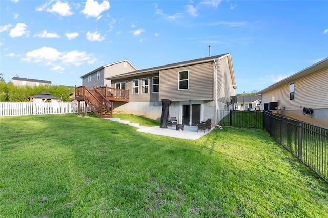 back of house with a fenced backyard, a wooden deck, a yard, and stairway