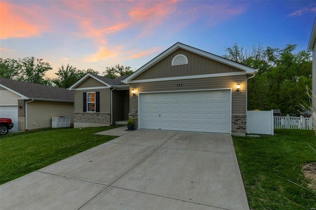 ranch-style house with a lawn, board and batten siding, fence, an attached garage, and concrete driveway