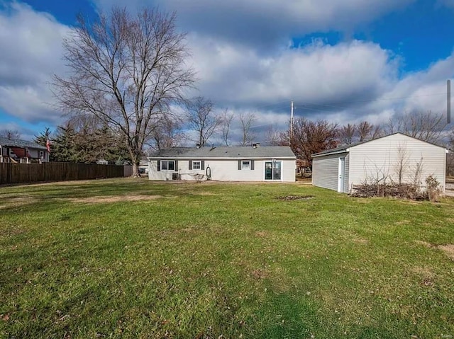 rear view of property with a yard, an outbuilding, and fence