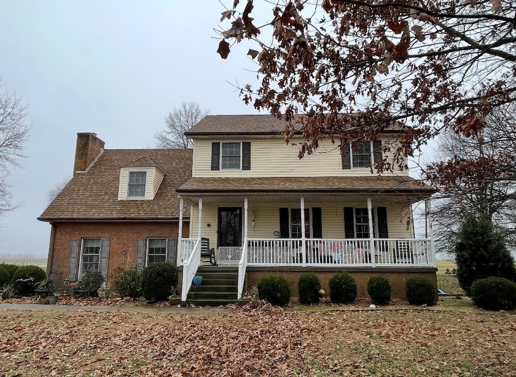 view of front of home with a chimney and covered porch