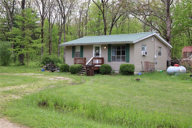 view of front of home featuring metal roof, cooling unit, and a front yard