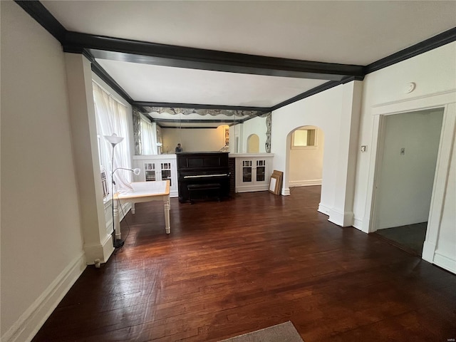unfurnished living room with arched walkways, wood finished floors, beamed ceiling, baseboards, and ornamental molding