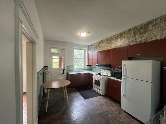 kitchen featuring white appliances, a sink, light countertops, and under cabinet range hood